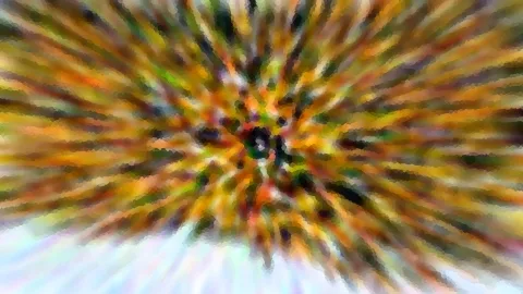 Abstrakte Aufnahme mit radialer Unschärfe: farbige Streifen in Gelb, Orange und Grün laufen von der dunklen Mitte nach außen, unten geht das Bild in helles Blau-Weiß über.