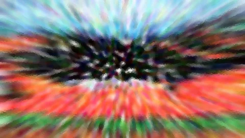 Abstraktes Bild mit radial verwischten Farbstrahlen in Blau, Rot, Orange und Grün, im Zentrum ein dunkler, fleckiger Bereich.