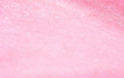 Nahaufnahme einer rosafarbenen Blütenblattoberfläche mit feinen hellen Glitzerpunkten