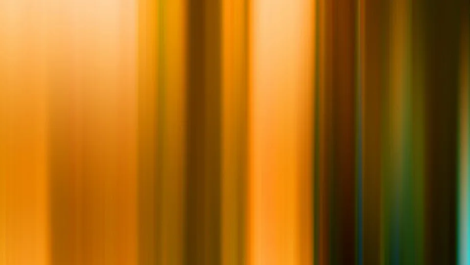 Unscharfe vertikale Streifen in Orange, Braun und Gelb, die von hell nach dunkel verlaufen, rechts am Rand ein schmaler grünlich-blauer Streifen.