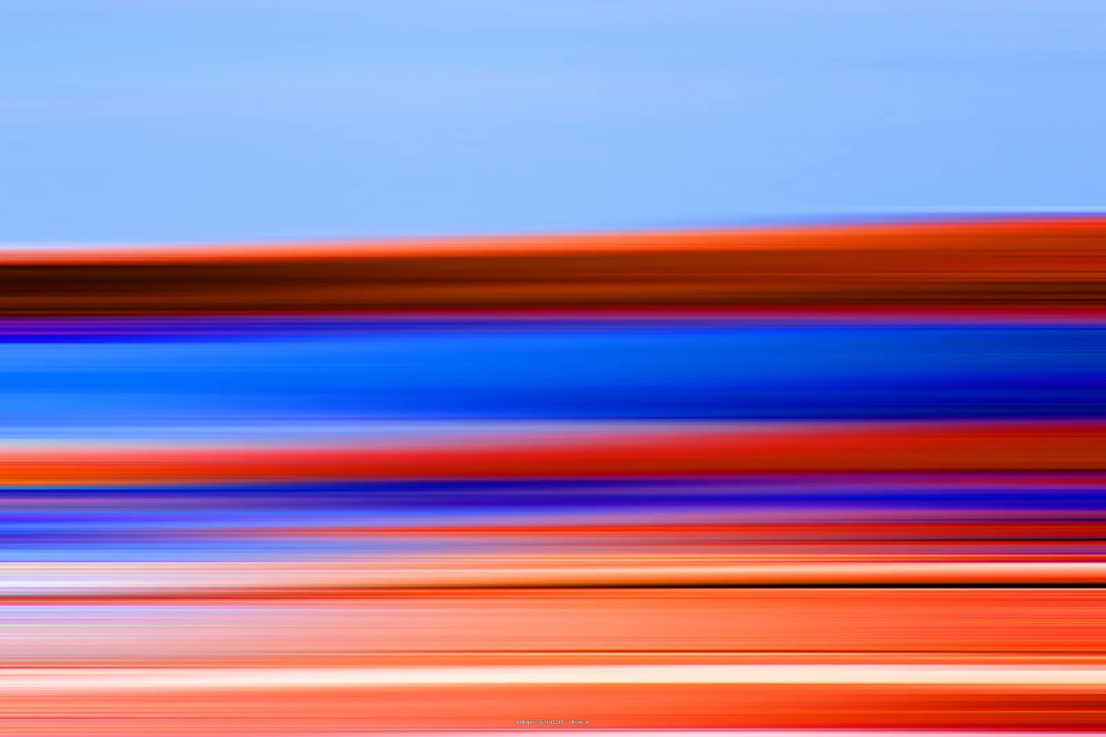 Horizontal verwischte Streifen in Blau, Orange, Rot und Violett, darüber ein hellblauer Himmel.
