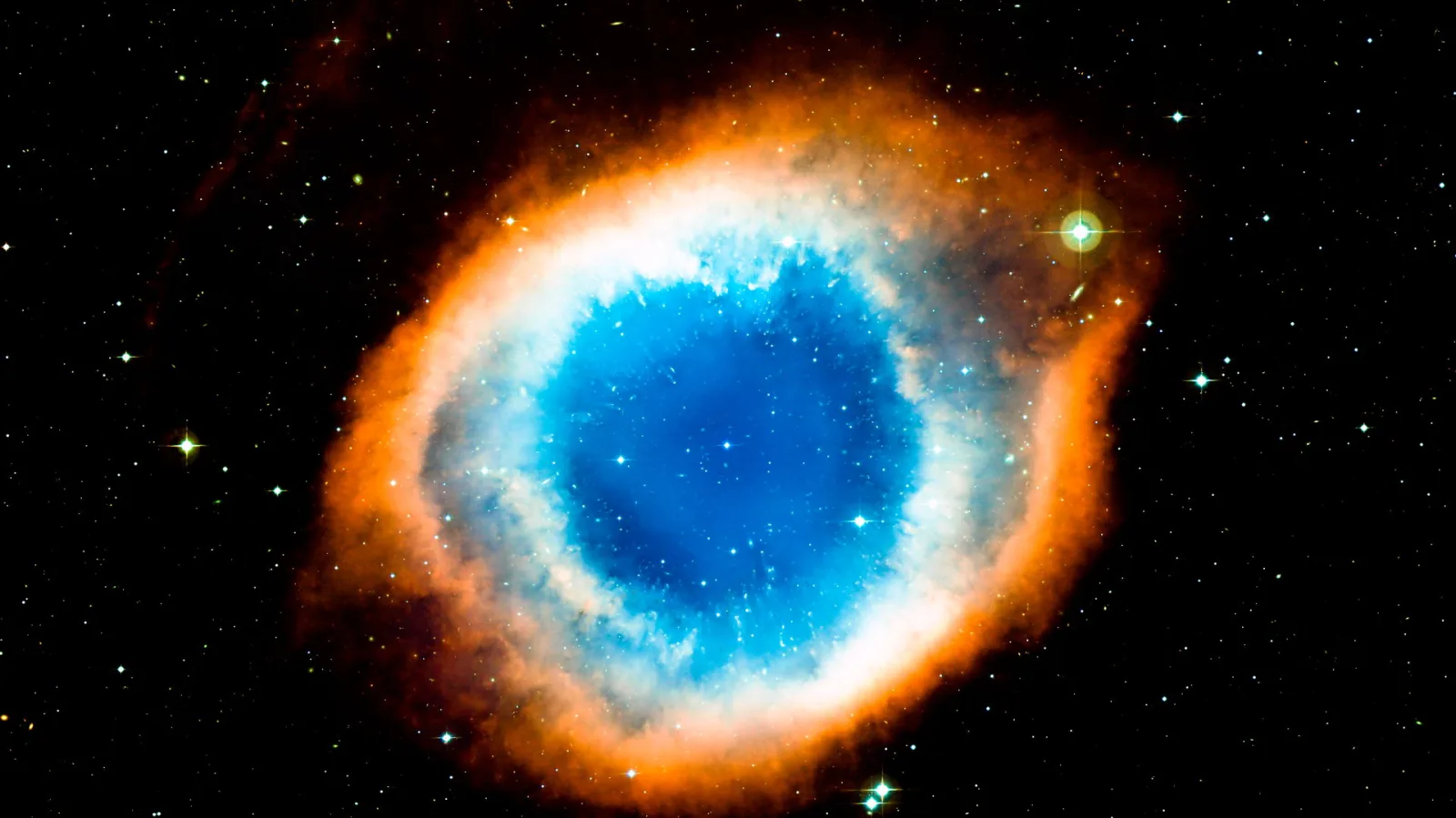 Runder Nebel mit blauem Zentrum und orangefarbenem Ring vor einem Sternenhimmel