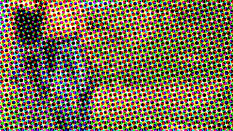 Dichtes Raster aus bunten Punkten in Rot, Grün, Blau und Gelb auf weißem Grund, mit einem dunklen, diagonal verlaufenden Bereich links.