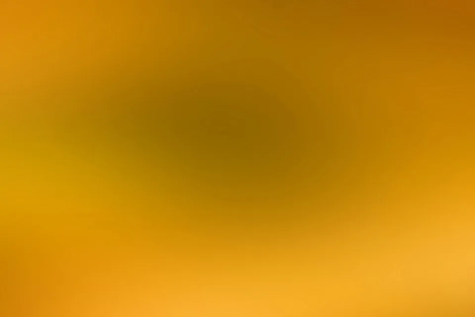 Weich verlaufender Farbverlauf in Gelb und Ocker, in der Mitte ein dunkler, bräunlicher Schatten, nach außen heller werdend.