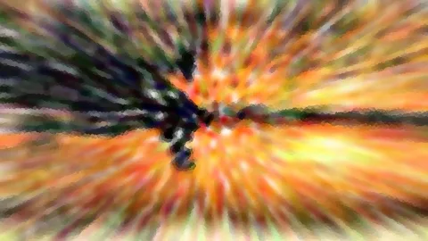 Abstrakte radiale Unschärfe in Orange, Gelb und Grün, mit einer dunklen Silhouette nahe der Bildmitte.