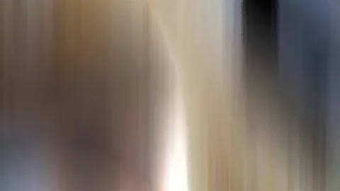 Abstrakte, vertikal verwischte Farbflächen in Beige, Braun und Grau mit einem hellen Lichtstreifen unten in der Mitte und einem dunklen Bereich oben rechts.