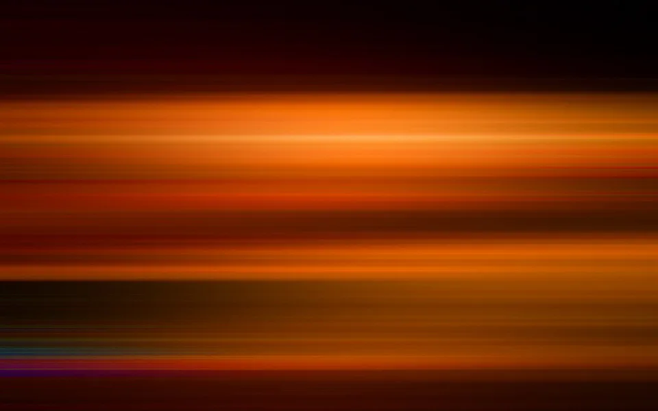 Horizontal verwischte Streifen in Orange, Rot und Dunkelbraun, oben und unten dunkel, unten links kühle blaue und violette Schlieren.