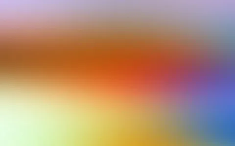 Unscharfer Farbverlauf mit warmen Orange- und Rottönen in der Mitte, gelben Tönen unten links und blauen Flächen rechts.