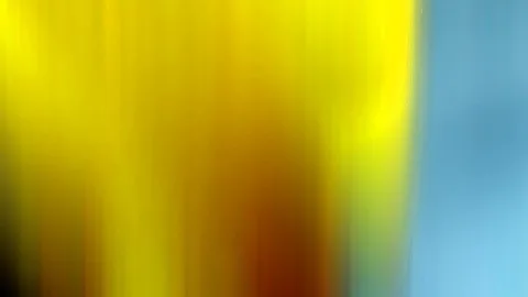Abstrakte Bewegungsunschärfe mit vertikalen gelben und orangefarbenen Schlieren, rechts eine ruhige hellblaue Fläche.