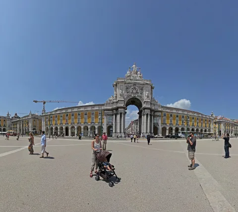 Der Triumphbogen Arco da Rua Augusta auf dem Praça do Comércio in Lissabon, davor Menschen auf dem hellen Platz unter blauem Himmel.