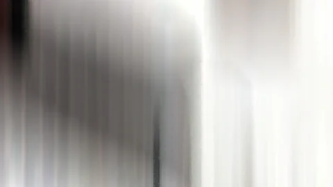 Verschwommene vertikale Streifen in Grau und Weiß, links ein dunkles Band, rechts helle Fläche.