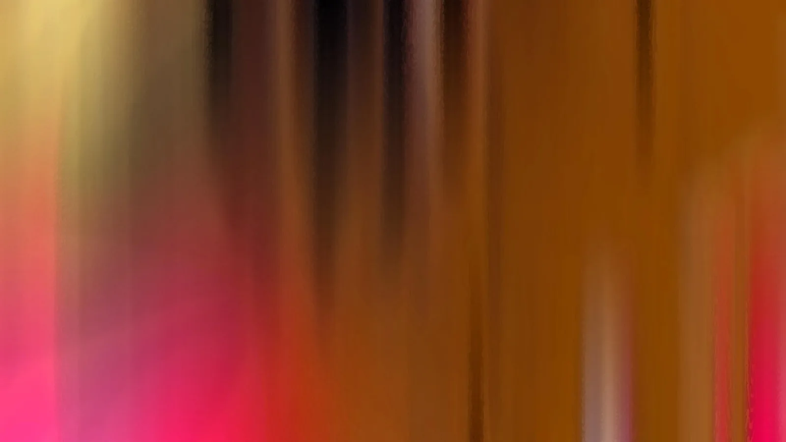Abstrakte, vertikal verwischte Farbflächen in Orange, Braun, Pink und Gelb, dunklere Streifen oben in der Mitte.