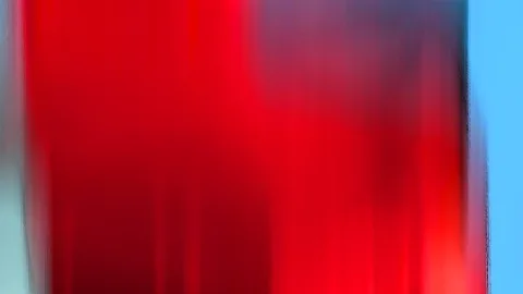 Abstrakte Aufnahme mit vertikal verwischten roten Schlieren, rechts ein schmaler blauer Himmelsstreifen.