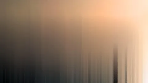 Abstrakte, vertikal verwischte Fläche mit Übergang von dunklem Grau links zu warmem Orange und hellem Beige rechts oben.