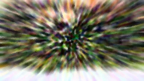 Abstrakte, stark verwischte Aufnahme mit radialen Streifen in Grün, Violett und Weiß, die von einem dunkleren Zentrum nach außen strahlen; unten hellt sich das Bild auf.
