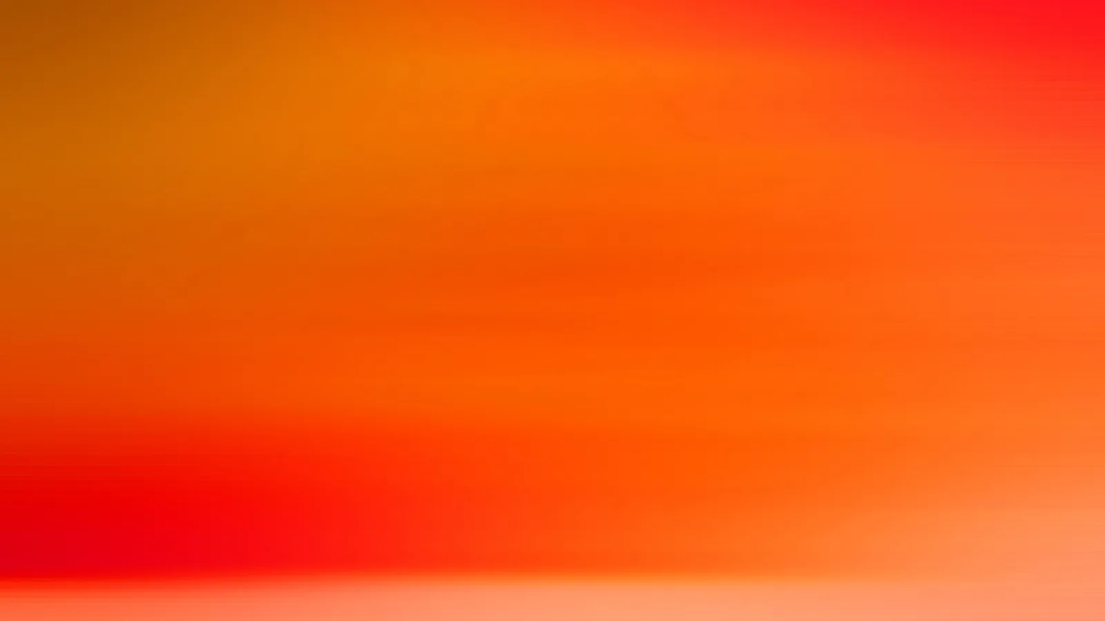 Verschwommene horizontale Streifen in Orange, Rot und Gelb, unten hellt sich das Bild auf Lachs auf.