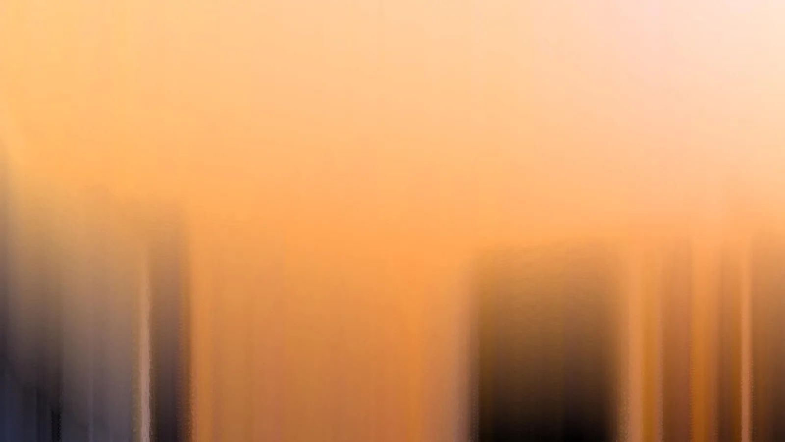 Verschwommene vertikale Streifen in Orange und Creme, unten links und Mitte dunkle Flächen.