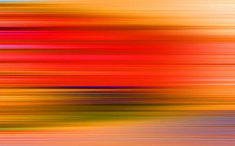 Abstrakte horizontale Streifen in Rot, Orange und Gelb, unten grünlich und mit einzelnen blauen Linien, wie durch Bewegungsunschärfe entstanden.