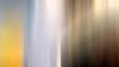 Abstrakte Aufnahme mit senkrechten, verwischten Streifen in Gelb, Weiß, Grau und Braun, links ein warmer gelber Bereich, rechts dunklere Brauntöne.
