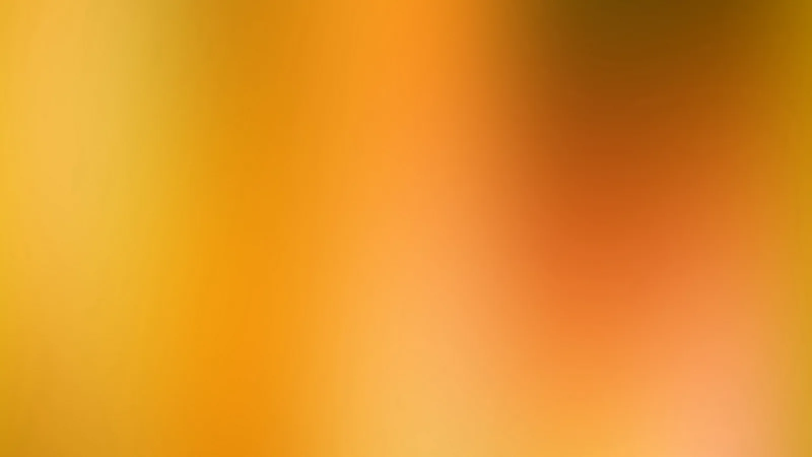 Weich verschwommener Farbverlauf von Gelb über Orange bis Braun und Rosa, dunkler Bereich oben rechts.