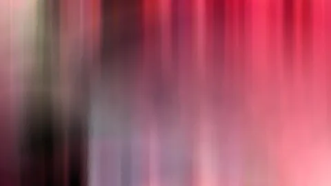Abstrakte, stark verwischte Aufnahme mit senkrechten Schlieren in Rot, Rosa, Violett und Grau, links dunkler, rechts heller.