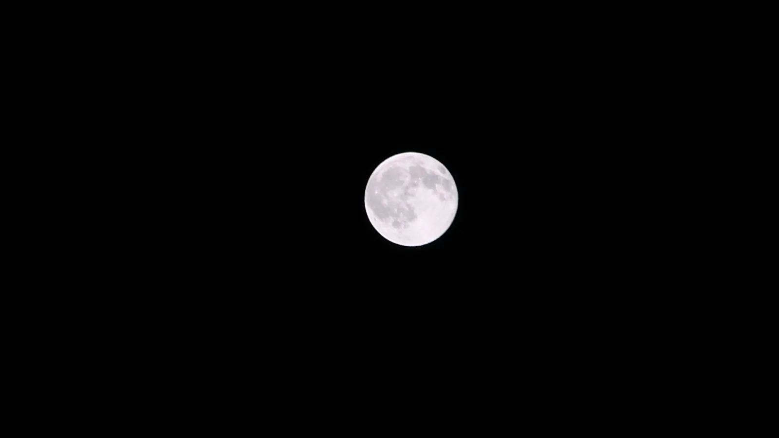 Heller Vollmond mit sichtbaren Kratern, mittig vor fast schwarzem Nachthimmel