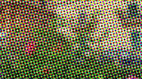 Dichtes Raster aus farbigen Punkten in Rot, Gelb, Blau, Magenta, Cyan und Schwarz auf grünem Grund, im oberen rechten Bereich heller werdend.