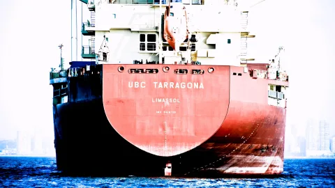 Heck eines roten Frachters mit dem Namen UBC Tarragona auf dunkelblauem Wasser vor hellem Dunst.