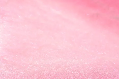 Rosafarbene, unscharfe Oberfläche mit feinen glitzernden Lichtpunkten, die von hell nach dunkel verlaufen