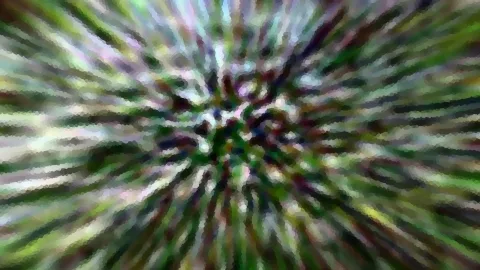Stark verwischte Aufnahme mit radial von der Mitte nach außen laufenden Streifen in Grün, Violett und Weiß.