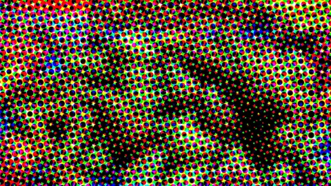 Dichtes Raster aus bunten Punkten in Rot, Grün, Blau und Gelb, dazwischen große schwarze Flecken.