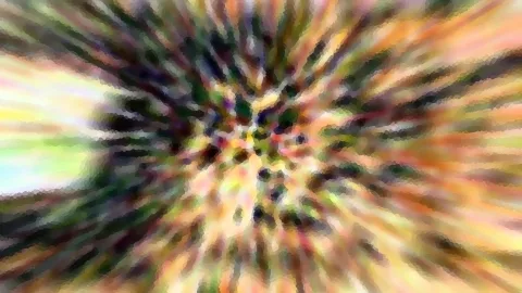 Abstrakte, radial verwischte Farbexplosion mit bunten Streifen in Gelb, Grün, Orange und Dunkelgrau, die sich von einem dunkleren Zentrum nach außen ziehen.