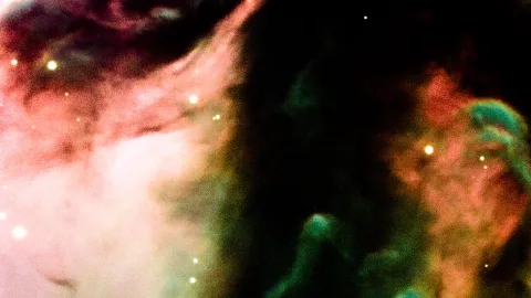 Rosafarbene und türkisfarbene Gaswolken vor einem dunklen Himmel, verstreut leuchten einzelne helle Sterne.
