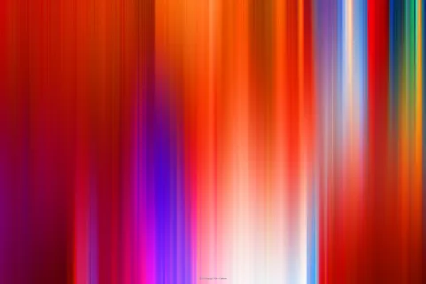 Abstrakte, vertikal verwischte Lichtstreifen in Rot, Orange, Violett, Blau und Weiß, die in der Bildmitte zu einem hellen Glühen zusammenlaufen.