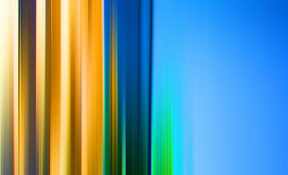 Vertikale, verwischte Streifen gehen von Gelb und Orange links in Grün und Blau rechts über, mit einer ruhigen blauen Fläche am rechten Rand.