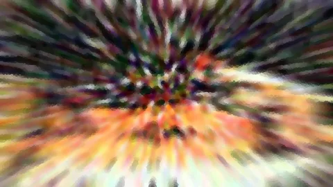 Abstraktes Bild mit radialem Zoomeffekt: bunte Farbstreifen aus Grün, Lila, Orange und Gelb laufen von einem dunklen Zentrum nach außen, die Kanten wirken mosaikartig.