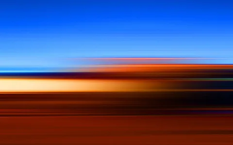 Abstrakte Komposition aus horizontalen Streifen: oben tiefblauer Himmel, darunter orange, cremefarbene und dunkelbraune Bänder, die wie Lichtspuren verwischen.