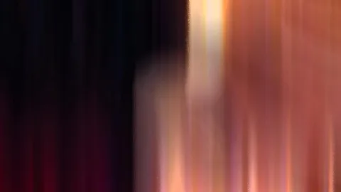 Stark verwischte vertikale Streifen: links dunkel und fast schwarz, rechts warm in Orange, Rosa und Gold mit einem hellen Lichtband in der Mitte.