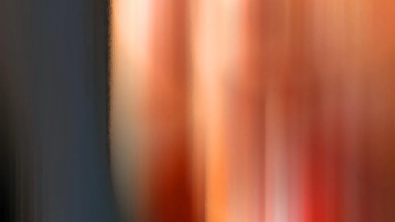 Abstrakte, stark verwischte senkrechte Streifen: links dunkles Graublau, rechts Orange, Rot und Cremeweiß.