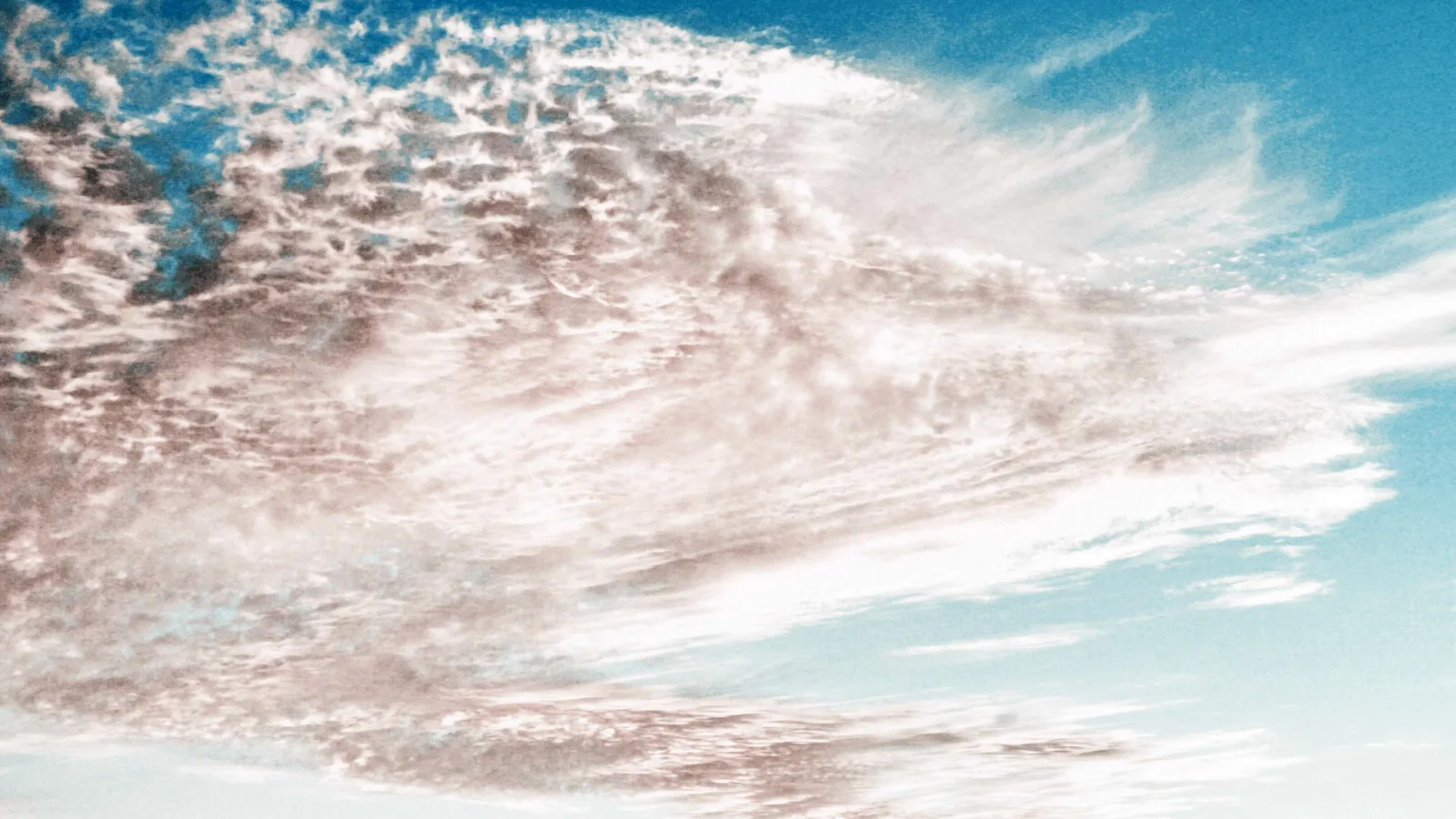 Feine, streifige Schleierwolken ziehen diagonal über einen blauen Himmel, rechts ist der Himmel fast wolkenfrei.