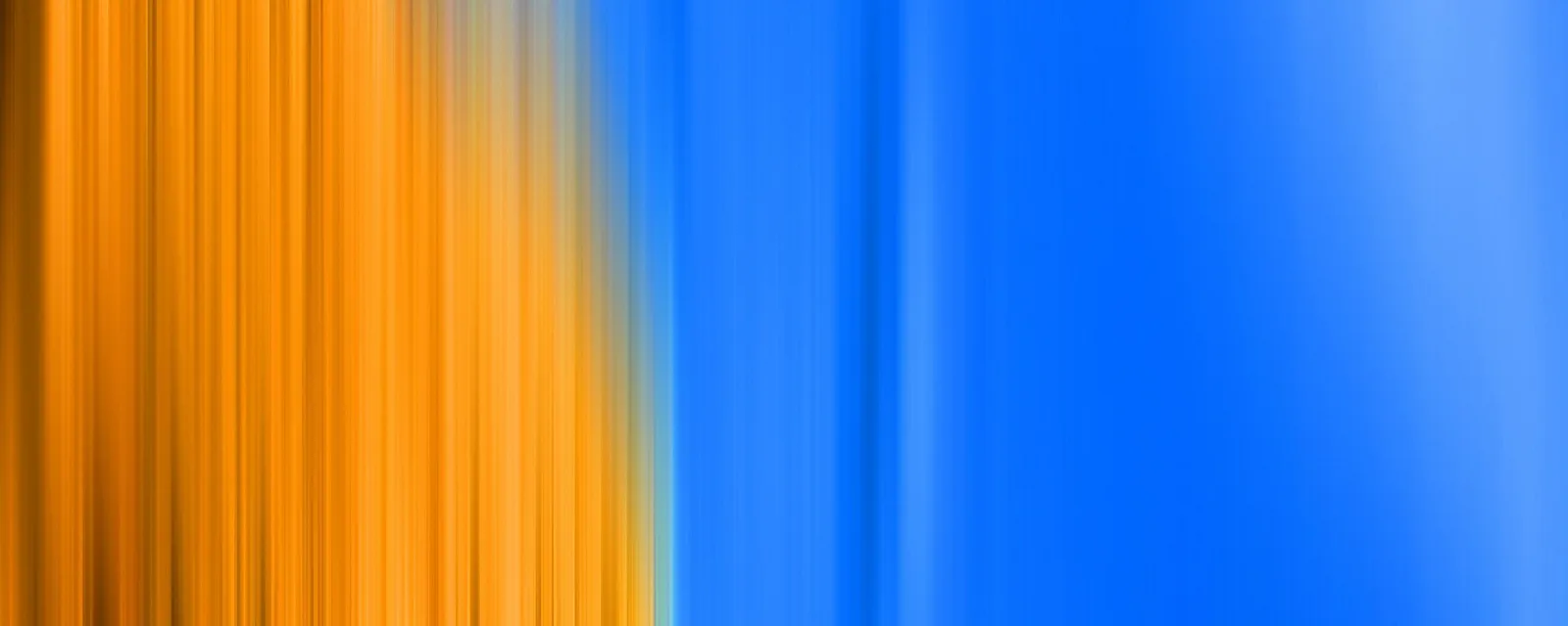 Abstrakte Aufnahme mit vertikalen, verwischten Streifen: links leuchtendes Orange, rechts ein tiefes Blau, das in helles Hellblau übergeht.