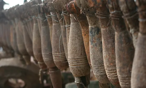 Reihe rostiger Artilleriegranaten, die an Drähten hängen, in grau-brauner Farbe mit Abnutzungsspuren