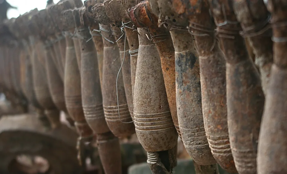 Reihe rostiger Artilleriegranaten, die an Drähten hängen, in grau-brauner Farbe mit Abnutzungsspuren