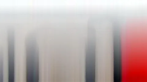 Verwischte vertikale Streifen in Grau, Weiß und Schwarz, rechts ein leuchtend roter Bereich.