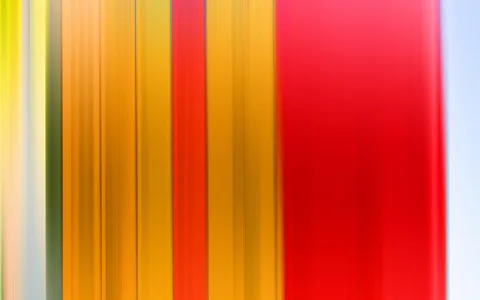 Vertikal verwischte Streifen in Gelb, Orange, Rot und Hellblau nebeneinander, ohne erkennbare Gegenstände.