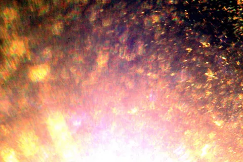 Unscharfe Nahaufnahme einer glitzernden Oberfläche in Gold, Orange und Rosa mit winzigen Lichtreflexen