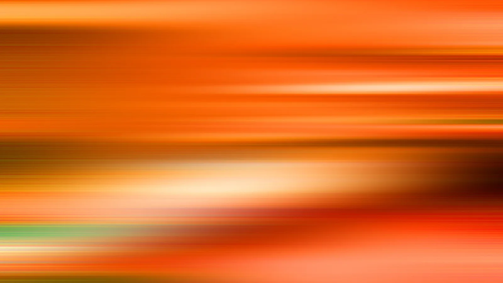 Horizontale, verwischte Lichtstriche in Orange, Gelb und Weiß, durchzogen von einem grünen Streifen am unteren Rand.