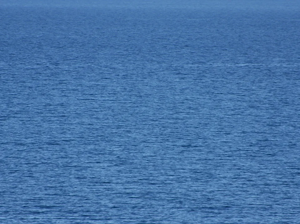 Blaue, leicht gekräuselte Meeresoberfläche, am oberen Rand fast unmerklich in den Horizont übergehend.