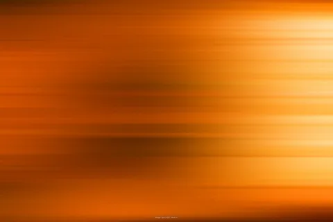 Abstrakte horizontale Bewegungsunschärfe in Orange- und Brauntönen, rechts hell leuchtend, links dunkler.