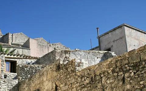 Alte Steinmauern und verputzte Häuser vor blauem Himmel in Erice, Sizilien.